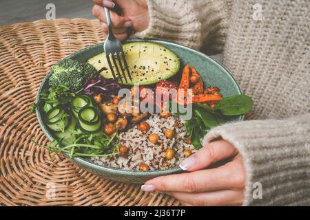 Woman eating healthy buddha bowl. Buddha bowl with rice, quinoa, avocado and vegetables Stock Photo
