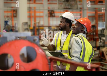 Engineer team safety check machine working together happy smile in factory. Stock Photo