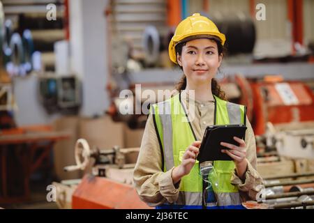 Asian working woman worker, portrait smile engineer lady standing with tablet. Stock Photo