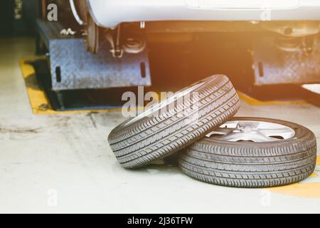 Car in under service lifted for tire replace in auto garage, checking vehicle brake and suspension for safety travel. Stock Photo