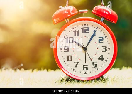 Alarm clock red Classic Vintage Retro Color Tone on Wood Table with Sun Light Stock Photo