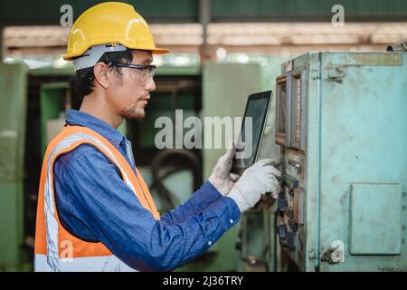 Engineer worker program setup CNC machine in metal industry factory with tablet technology. Stock Photo