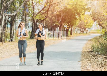 Girls jogging outdoor workout in the green park. Beautiful two Asian woman friend running outdoors. Stock Photo