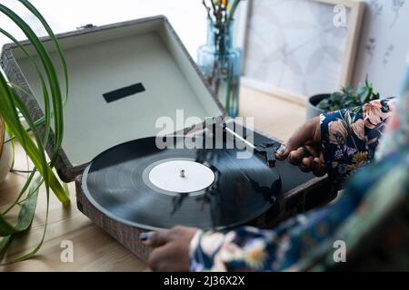 Unrecognizable young man standing in front of window turning on music using on vinyl record player Stock Photo