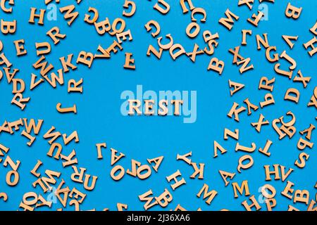 Word REST made out of wooden letters on bright blue background. Motivational Words Quotes Concept. Inspirational phrase Stock Photo