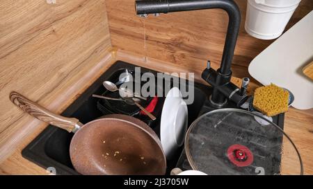 Heap of dirty dishes in sink and broken faucet leaking Stock Photo