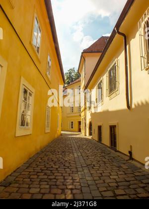 Yellow Buildings in Prague Alley, the Old City, Praha Narrow Street with cobblestones, Alleyway Medieval Street, Jewish Quarter, Czech Republic Stock Photo