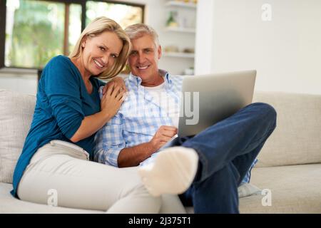 Bonding while browsing. Portrait of a mature couple using a laptop together at home. Stock Photo