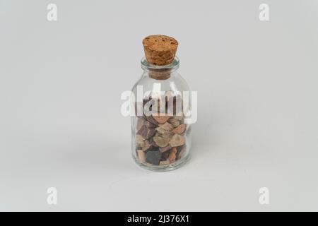 Small rocks in glass bottle with cork stopper isolated on white background, for remembrance, broken sand stones in glass bottle, saving memory on jar, Stock Photo
