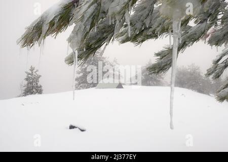 focus on an icicle, on background blurred view of winter wild camping in Etna Park, Sicily Stock Photo