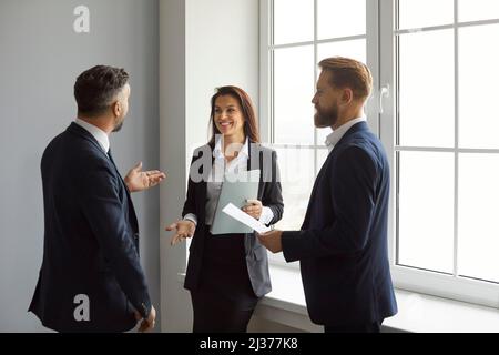 Smiling business people discuss work, project strategy and exchange ideas together. Stock Photo