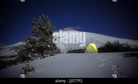 night stars on illuminated yellow tent on the snow and Etna Mount, Sicily Stock Photo