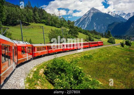 Local train at the Surava village in albula valley in alps mountains, Graubunden, Grisons Mountain. The glacier express train from Zermatt to St.Morit Stock Photo