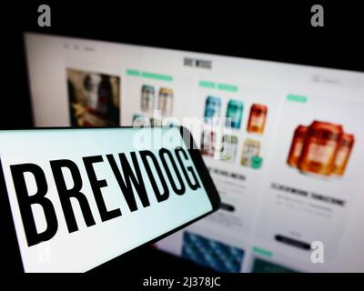 Cellphone with logo of British brewery company BrewDog plc on screen in front of business website. Focus on left of phone display.