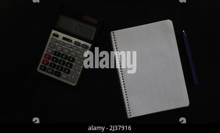 Concept black table with calculator and notebook, accounting with blank and pen, calculating, isolated on black background, top view Stock Photo