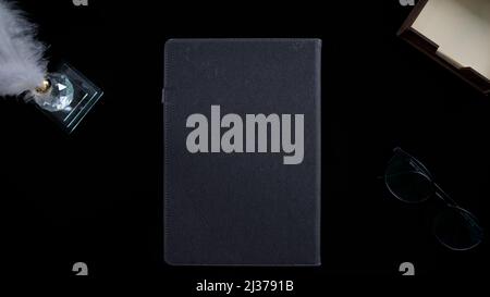 Concept black table with grey notebook and glasses, isolated on black background, top view, table decorations Stock Photo