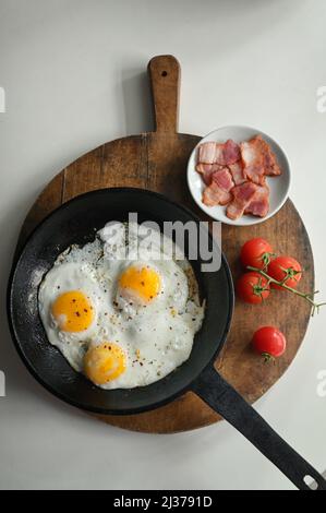 Fried Eggs In A Frying Pan, Bacon and Cherry Tomatoes Stock Photo