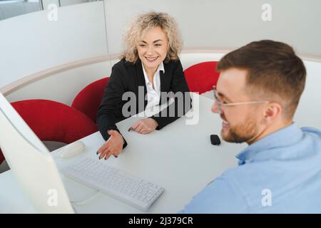 Woman car sales manager showing options to a male client on computer Stock Photo