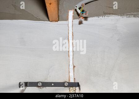 A furrow cut out in the facade of the house from polystyrene for an electric cable for connecting the led lamp. Stock Photo