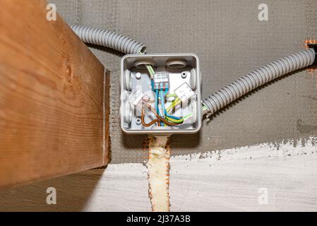 Electric cables for LED lighting connected in an electrical box on the facade of the building, visible cable groove filled with mounting foam. Stock Photo