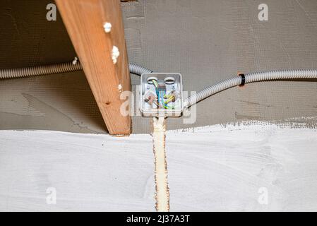 Electric cables for LED lighting connected in an electrical box on the facade of the building, visible cable groove filled with mounting foam. Stock Photo