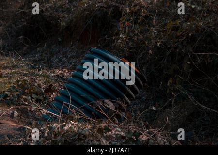 Pipe coming out of the ground, nature and environmental pollution idea, autumn in the forest concept, dirty sewage from the plastic pipe Stock Photo