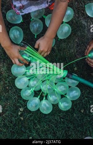 kids filling up green water balloons in the summer, backyard fun Stock Photo