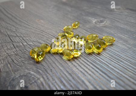 The oil fish laying on the wooden table. Yellow oil fish capsules close up photo. Stock Photo