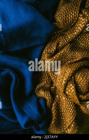 deep, rich jewel tone cobalt blue fabric next to gold sequined cloth scarf Stock Photo