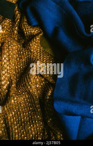 deep, rich jewel tone cobalt blue fabric next to gold sequined cloth scarf Stock Photo