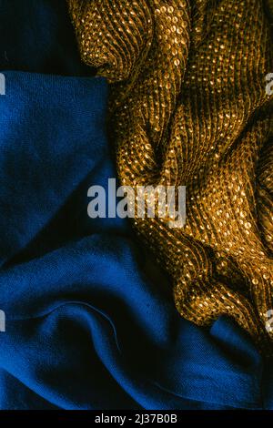 deep, rich jewel tone cobalt blue fabric next to gold sequined cloth scarf Stock Photo