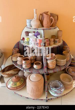 Hand made traditional ceramic bowls and other vessels on display on a wooden shelf. Stock Photo