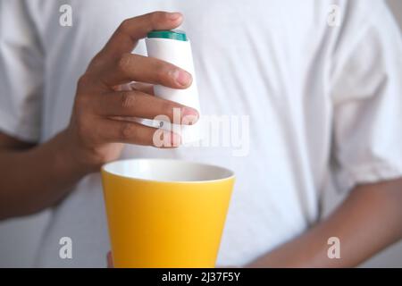 young man putting artificial sweetener in tea, Stock Photo
