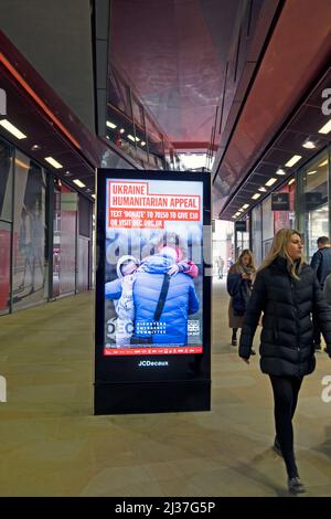 DEC Ukraine Humanitarian Appeal fundraising charity poster electronic advert and shoppers at One New Change in City of London England UK March 2022 Stock Photo