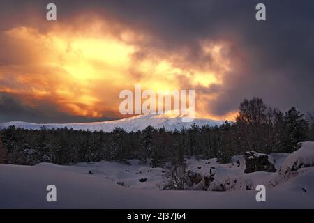 dramatic light in the sky at the sunset on snow covered Etna Mount, Sicily Stock Photo