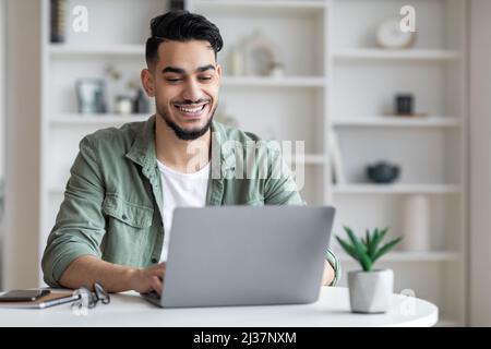 Young arab male writer working on laptop computer at home office Stock Photo