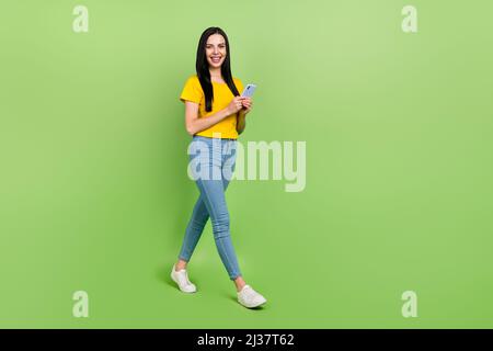 Full size profile portrait of charming positive person hold telephone isolated on green color background Stock Photo