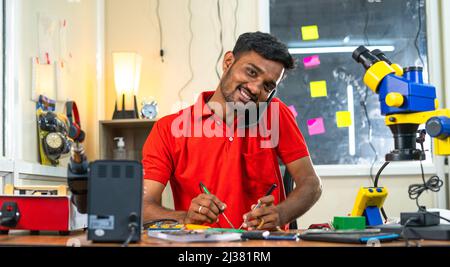 Mobile technician working with talking on mobile phone with customer at workshop - concept of relaxation, customer service and communication. Stock Photo