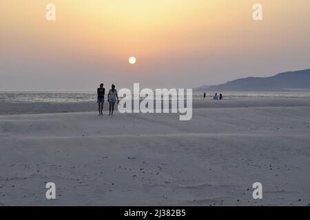 Tourists walking on the Playa de Los Lances beach at sunset in Tarifa Andalusia Spain. Stock Photo