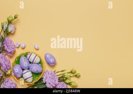 Easter eggs in a basket bouquet of purple flowers on a yellow background with place for text. Stock Photo