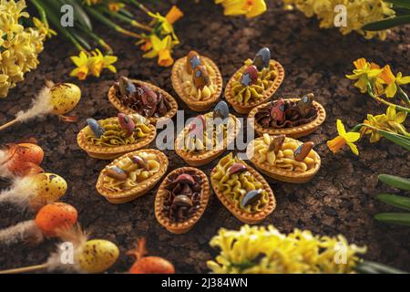 Easter tartlets with different cream filling on Easter still life background Stock Photo