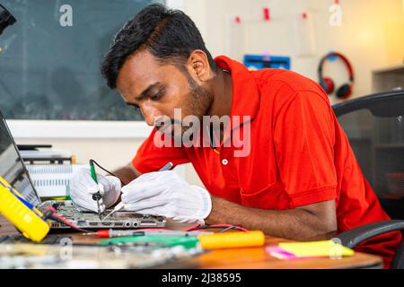 concentrated technician busy reparing laptop at workshop - concept of professional worker, skill jobs and repair service. Stock Photo