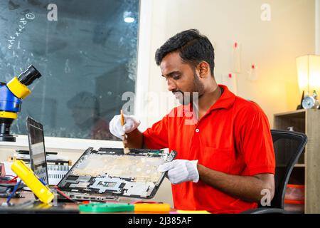 technician cleaning laptop panel using brush at repair shop - concept of repair service, professional occupation and skilled job. Stock Photo