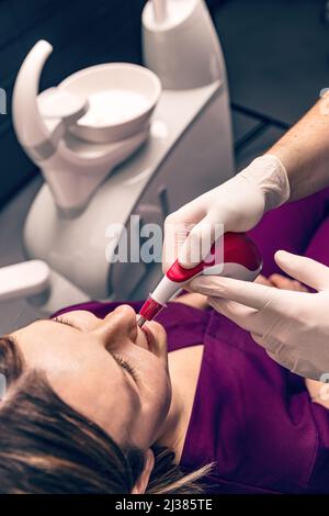 Dentist matching teeth color of woman with digital shade guide teeth color comparator Stock Photo