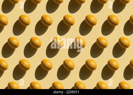 Repeating painted yellow eggs with a hard shadow on a yellow background, Easter background in pop art style, seamless pattern with Easter eggs Stock Photo