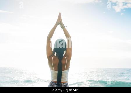 woman in sport clothes practicing yoga and meditating on beach in morning Stock Photo