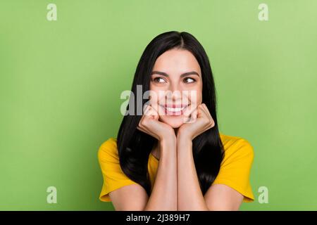 Photo of pretty cute lady dressed yellow t-shirt arms cheeks looking empty space isolated green color background Stock Photo