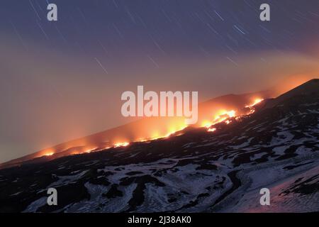 ETNA PARK, SICILY - MARCH 30, 2017: star trails on red lava river from the mouth opened at the base of the New SouthEast Crater, at an altitude of 3.0 Stock Photo
