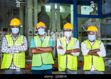 group of Confidently standing industrial workers with arms crossed by looking at camera at workplace - concept of workforce, occupation, blue collar Stock Photo