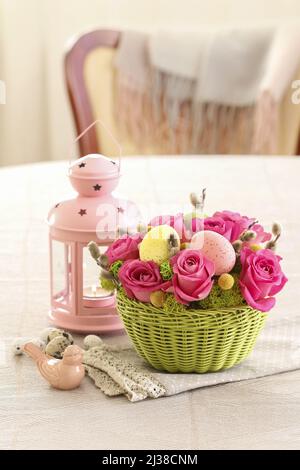 Florist at work: woman shows how to make Easter table decoration with roses, moss and catkins. Step by step, tutorial. Stock Photo